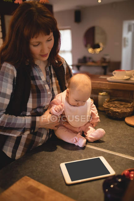 Mãe brincando com bebê na cozinha em casa — Fotografia de Stock