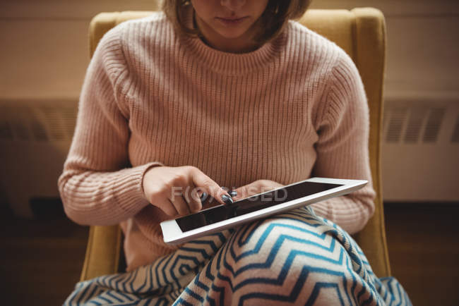 Frau sitzt mit digitalem Tablet im heimischen Wohnzimmer auf Stuhl — Stockfoto