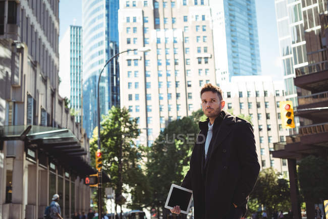Geschäftsmann mit digitalem Tablet, das tagsüber auf der Straße steht — Stockfoto