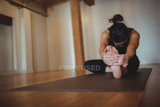 Жінка тягнеться на йога килимок у фітнес-студії — стокове фото