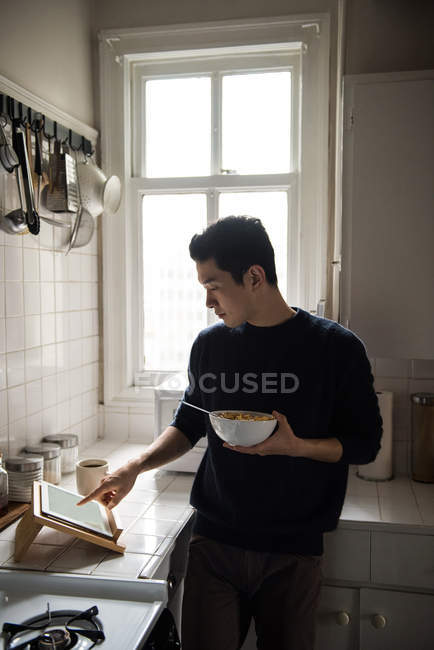Man using digital tablet while having breakfast at home — Stock Photo