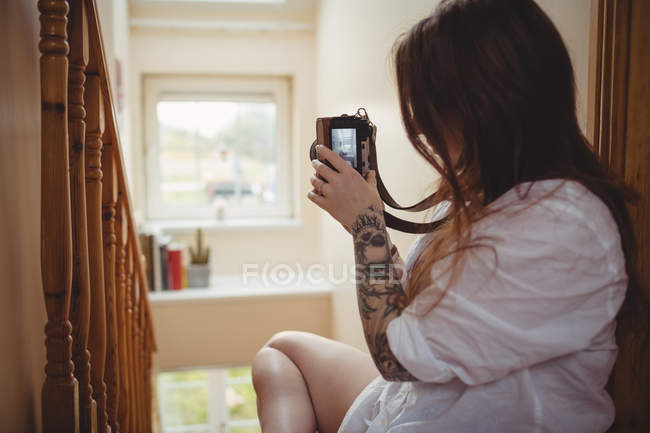 Donna che scatta foto sulla macchina fotografica digitale a casa — Foto stock