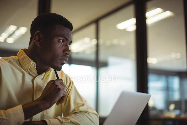 Homme d'affaires réfléchi travaillant sur ordinateur portable dans le bureau — Photo de stock