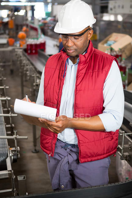 Empregado masculino confiante observando sobre produtos na fábrica de suco — Fotografia de Stock