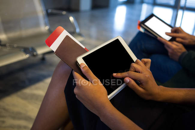 Средняя часть женщины, использующая цифровой планшет в зоне ожидания в аэропорту — стоковое фото