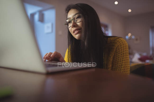 Woman using laptop on table in living room at home — Stock Photo