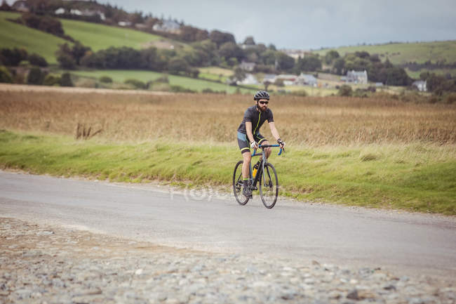 Atleta di sesso maschile in bicicletta sportiva su strada rurale — Foto stock