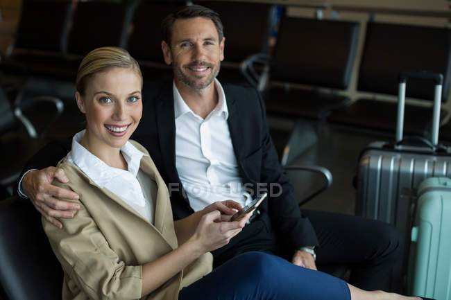 Retrato de casal feliz usando telefone celular no aeroporto — Fotografia de Stock