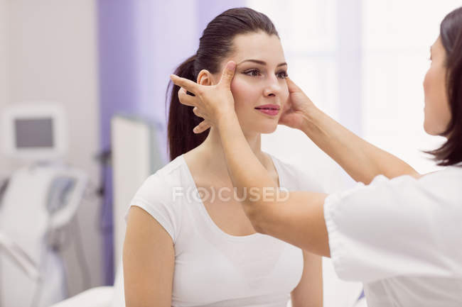 Dermatólogo examinando piel de paciente femenina en clínica - foto de stock