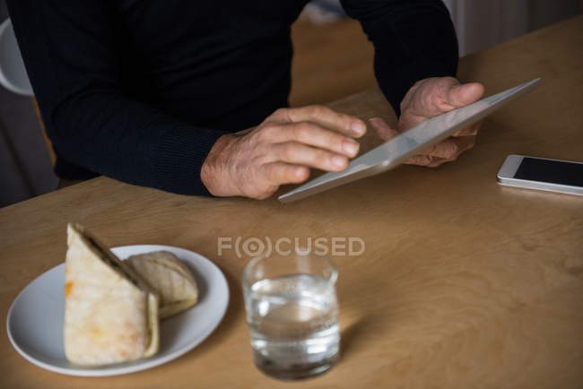 Mid-section of man using digital tablet at home — Stock Photo