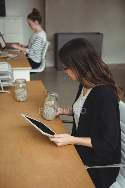Business executive looking at jar of pebbles in office — Stock Photo