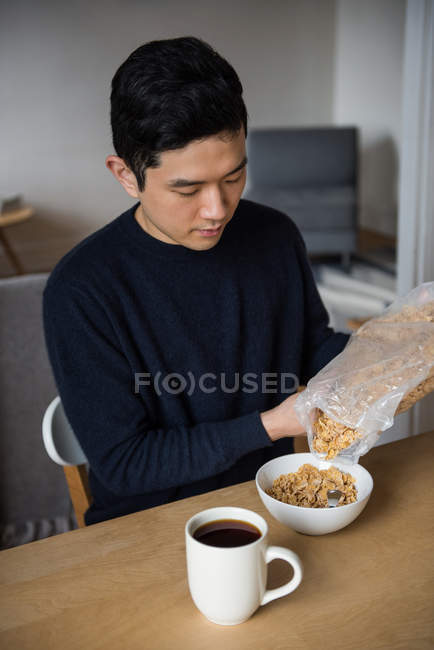 Man pouring cereals in bowl at home — Stock Photo