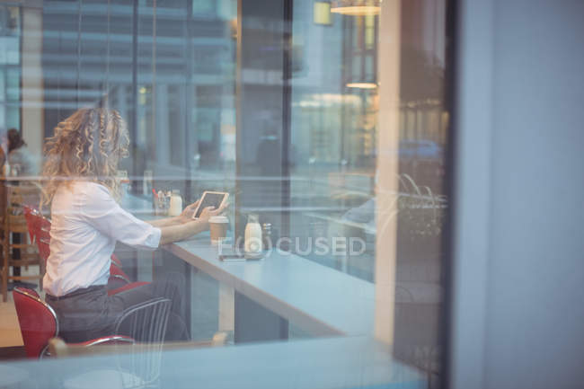 Femme d'affaires blonde utilisant une tablette numérique au comptoir de la cafétéria — Photo de stock