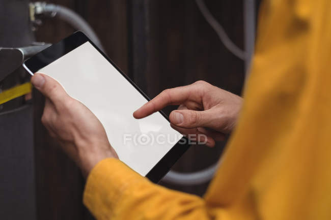 Close-up of man using digital tablet while making beer at home brewery — Stock Photo