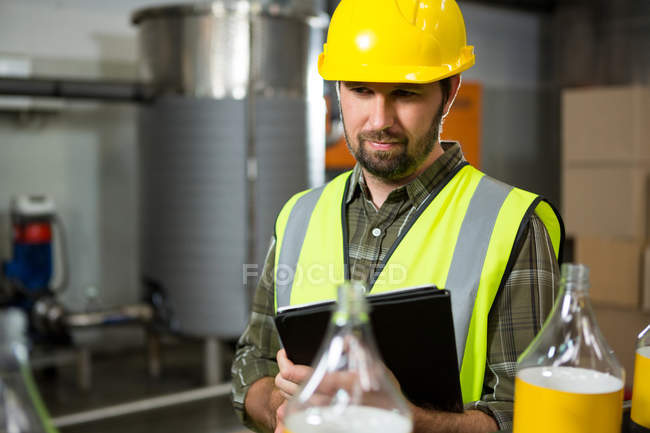 Thoughtful male worker using digital tablet in juice factory — Stock Photo
