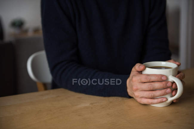 Sezione centrale dell'uomo che tiene una tazza di caffè nero a casa — Foto stock