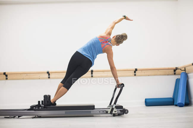 Rückansicht einer Frau, die im Fitnessstudio an einem Reformer trainiert — Stockfoto