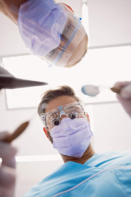 Низький кут зору стоматологів, які тримають зубні інструменти в стоматологічній клініці — стокове фото