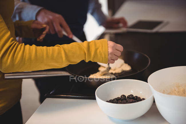 Casal usando tablet digital enquanto prepara cookies na cozinha em casa — Fotografia de Stock