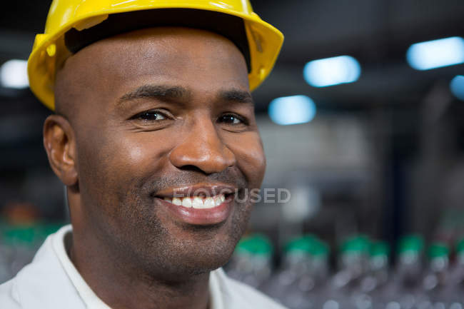 Nahaufnahme Porträt eines lächelnden männlichen Arbeiters mit hartem Hut im Lager — Stockfoto