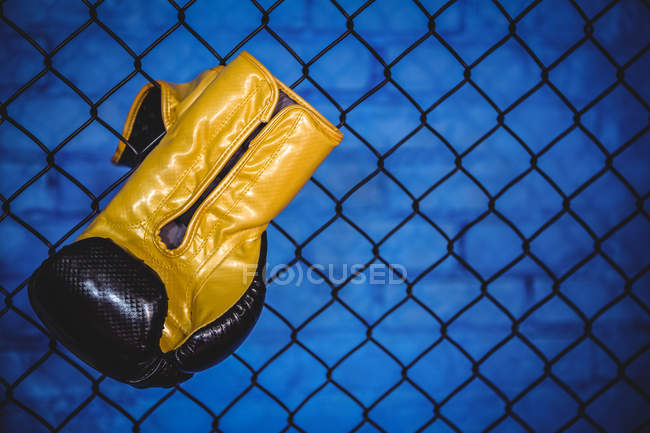 Boxing glove hanging on wire mesh fence in fitness studio — Stock Photo