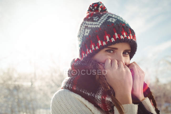 Portrait of beautiful woman in warm clothing covering her mouth with jumper — Stock Photo