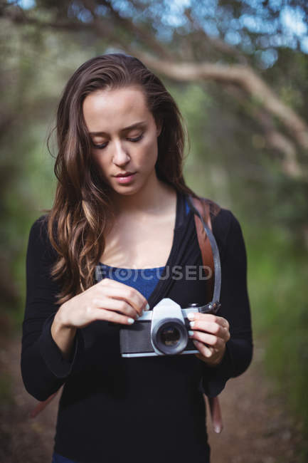 Belle femme debout avec caméra dans la forêt — Photo de stock