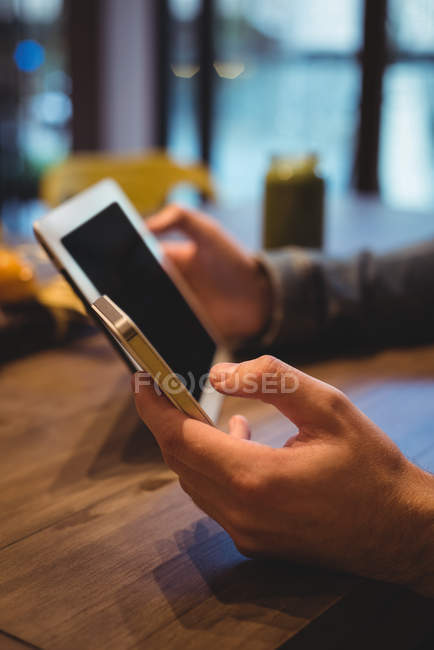 Крупним планом чоловік використовує цифровий планшет і мобільний телефон в кафе — стокове фото
