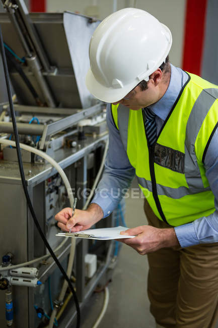 Technician examining machine at industrial factory — Stock Photo