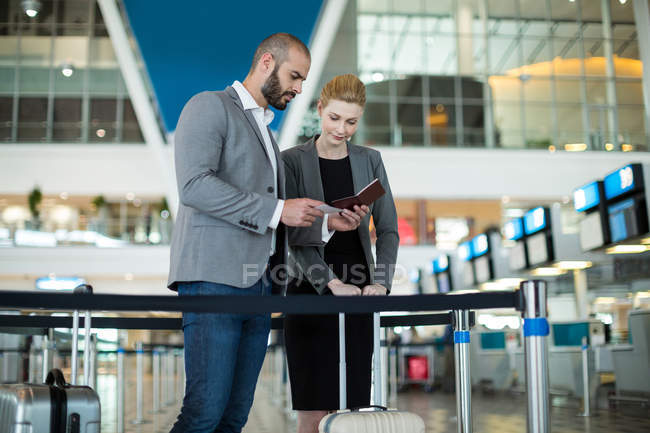 Деловые люди проверяют паспорт на стойке регистрации в терминале аэропорта — стоковое фото