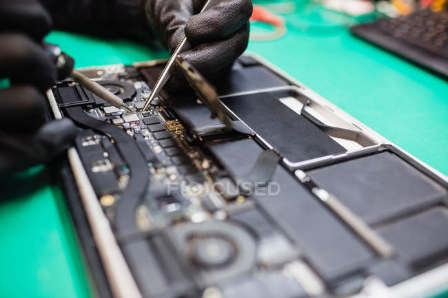 Close-up de microchip sendo fixado em uma placa de circuito usando ferro de solda — Fotografia de Stock