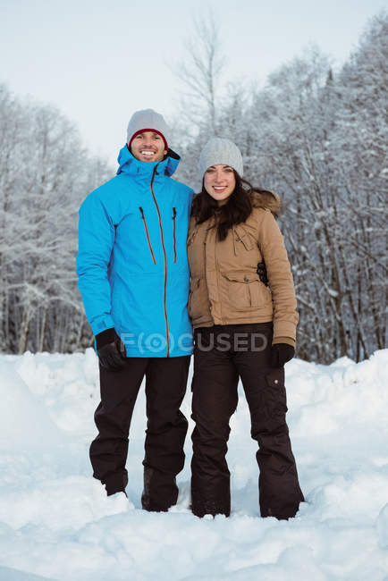 Ritratto di coppia sorridente in piedi su un paesaggio innevato — Foto stock