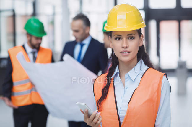 Portrait of a confident female architect holding mobile phone — Stock Photo