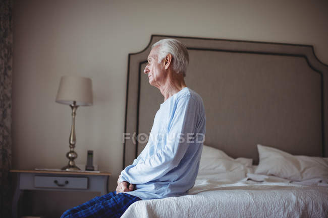 Nachdenklicher Senior sitzt zu Hause auf Bett im Schlafzimmer — Stockfoto