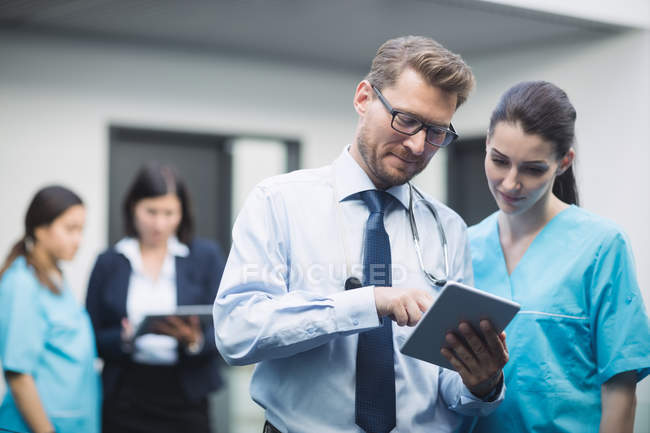 Arzt und Krankenschwester diskutieren über digitales Tablet im Krankenhausflur — Stockfoto