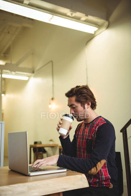 Mann benutzt Laptop beim Kaffeetrinken im Café — Stockfoto