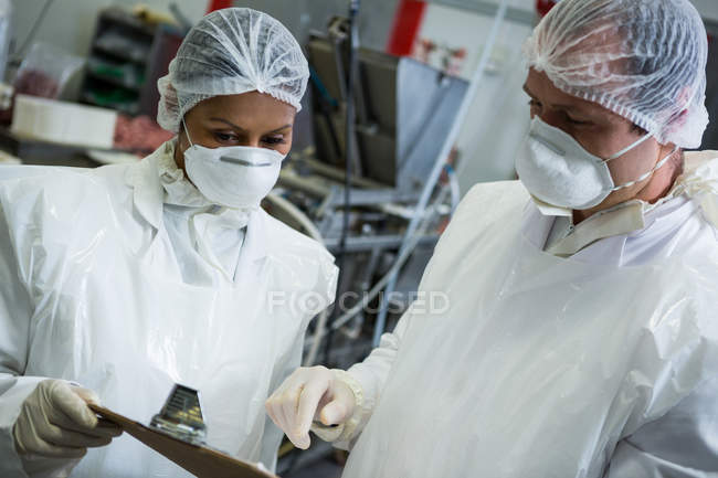 Butchers interacting with each other in meat factory — Stock Photo