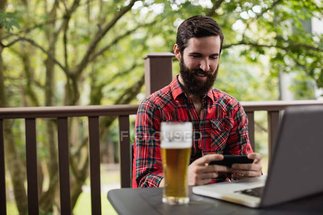 Homem usando telefone celular enquanto sentado no bar — Fotografia de Stock
