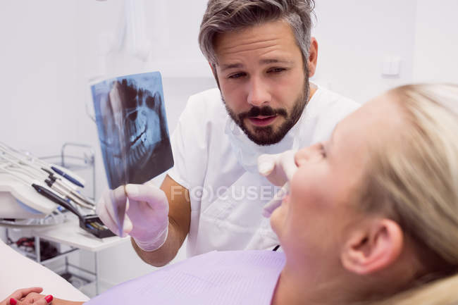 Стоматолог, який показує рентгенівський знімок пацієнтки у клініці — стокове фото