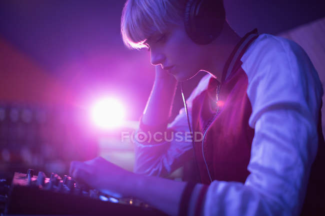 Femmina dj ascoltare le cuffie durante la riproduzione di musica nel bar — Foto stock