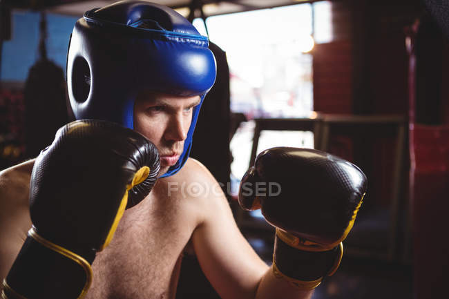 Boxer in helmet performing boxing stance in fitness studio — Stock Photo