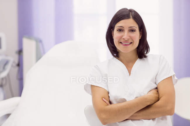 Portrait of female dermatologist standing with arms crossed in clinic — Stock Photo