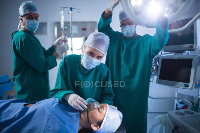 Surgeons adjusting oxygen mask on patient in operation theater of hospital — Stock Photo