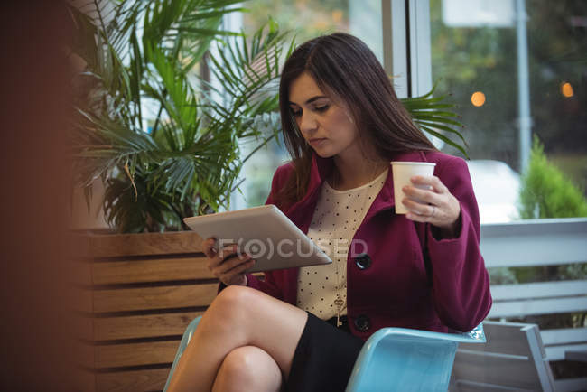 Красива бізнес-леді, використовуючи цифровий планшет, маючи каву в кафе — стокове фото