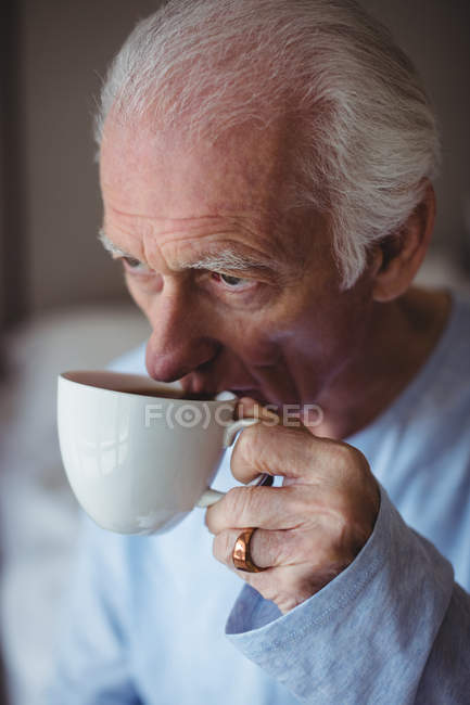 Close-up of senior man having coffee in bedroom at home — Stock Photo