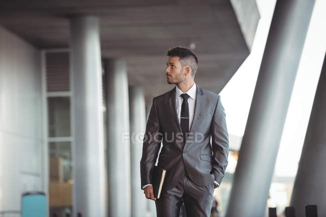 Empresário com um diário andando no corredor do escritório — Fotografia de Stock