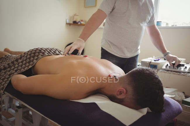 Fisioterapeuta realizando agulhas eletro-secas nas costas de um paciente na clínica — Fotografia de Stock