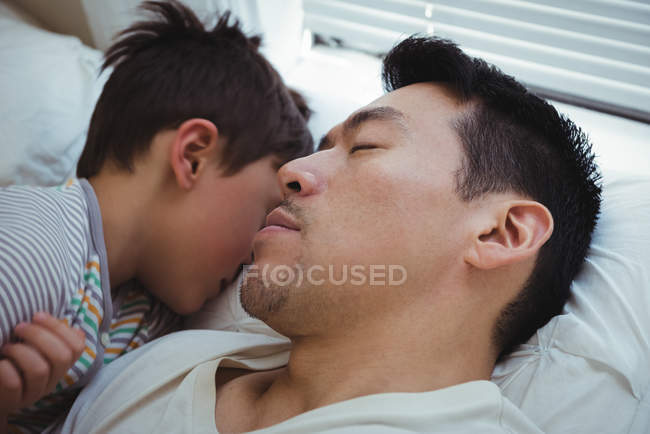 Père et fils dorment ensemble dans la chambre à coucher à la maison — Photo de stock