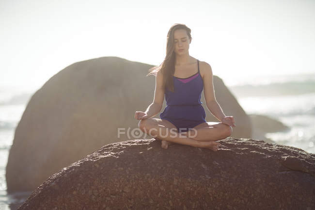 Schöne Frau, die an sonnigen Tagen Yoga auf Felsen macht — Stockfoto