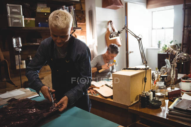 Artisanat attentif coupant le cuir dans l'atelier — Photo de stock